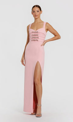 A woman stands against a plain background wearing the Mac Duggal 2293 long blush formal dress, featuring a sleeveless design, three jeweled bands on the bodice, and a high left-leg slit.