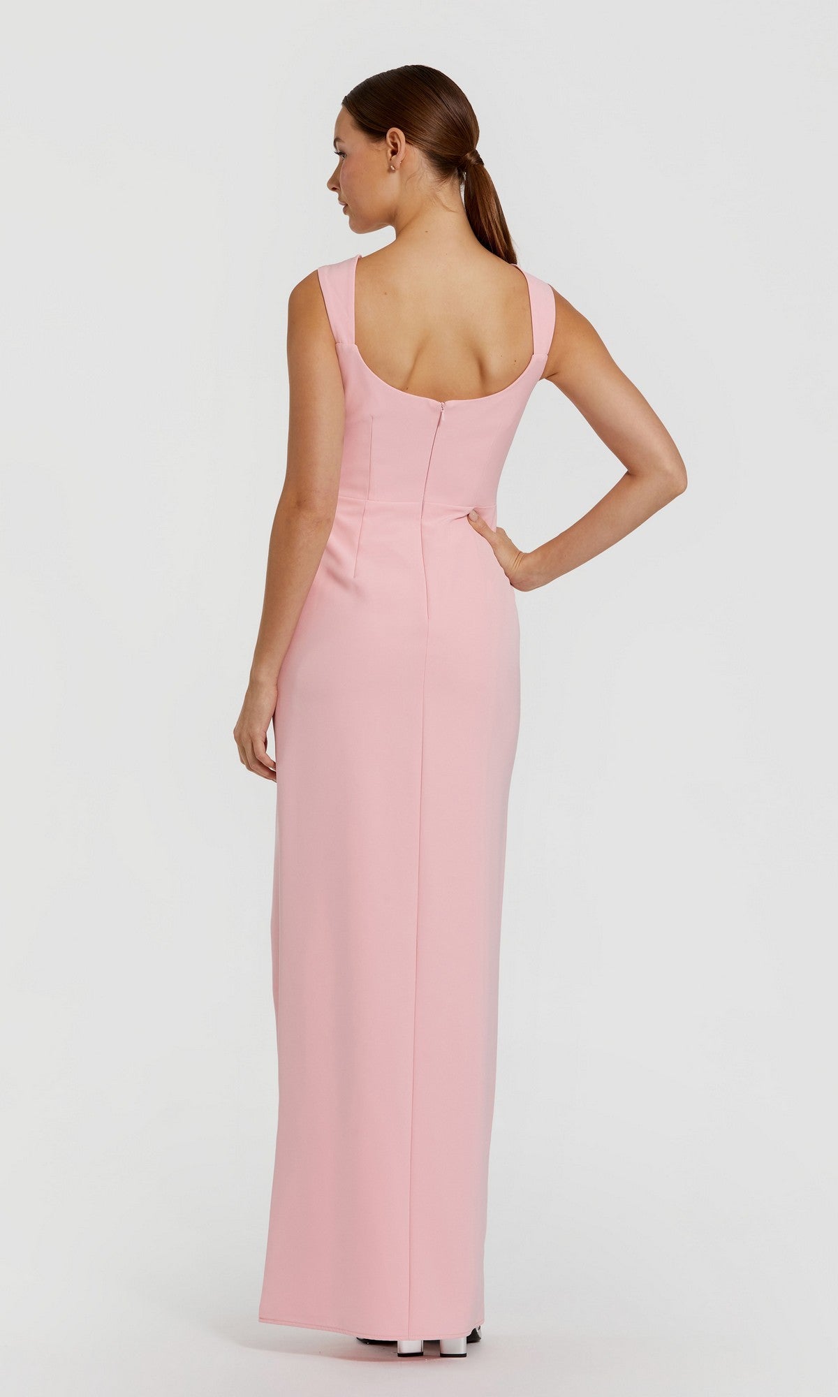 A woman faces away, wearing the Mac Duggal 2293—a long, sleeveless light pink formal dress with a fitted bodice and scoop back.