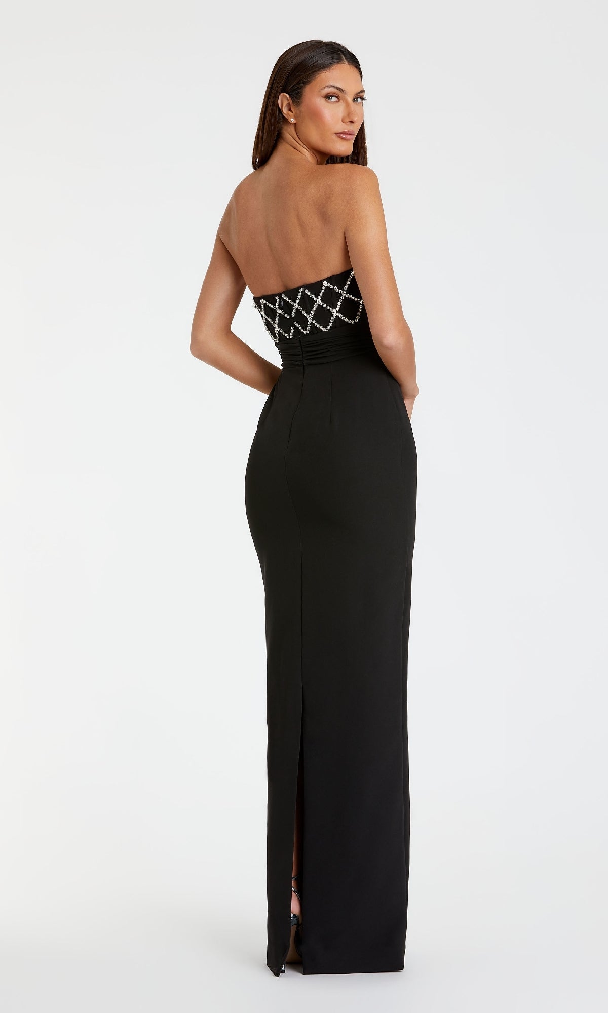 A woman stands, looking over her shoulder in the Mac Duggal 2294 Strapless Sweetheart Formal Gown, featuring a diamond-patterned bodice and back slit.