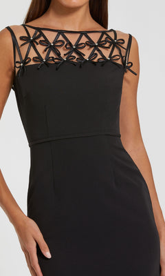 A woman wearing the Mac Duggal 2295 Bow-Neck Long Black Formal Dress, a sleeveless design with a sheer neckline and black bow accents along the top edge.