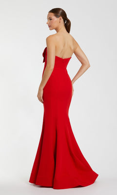 A woman poses with one hand on her hip in the Mac Duggal 2300 Strapless Long Black Formal Dress, featuring a fitted bodice and flared hem, set against a plain light background.