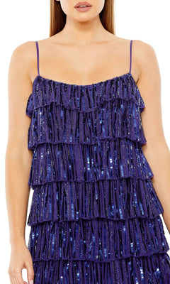 A woman wears the Mac Duggal 23001—a short, sleeveless semi-formal dress with thin straps, layered ruffles, and blue sequin beading.