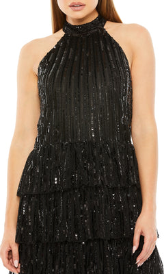 A woman models the Mac Duggal Short Black Homecoming Dress 23012, a sleeveless sequin dress with a halter neckline and tiered ruffle layers for a chic, party-ready style.