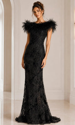 A woman wearing the Jovani 23030, a long black formal dress crafted from beaded floral lace with feathered shoulders, stands in a white, elegant interior space.