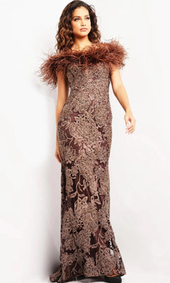 A woman wearing the Jovani 23030 long formal dress in brown, featuring floor-length beaded floral lace and an off-the-shoulder feathered neckline, stands against a plain white background.