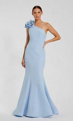 A woman in a powder blue Mac Duggal 2304 Flower One-Shoulder Formal Dress with a large floral shoulder detail stands against a plain white background.