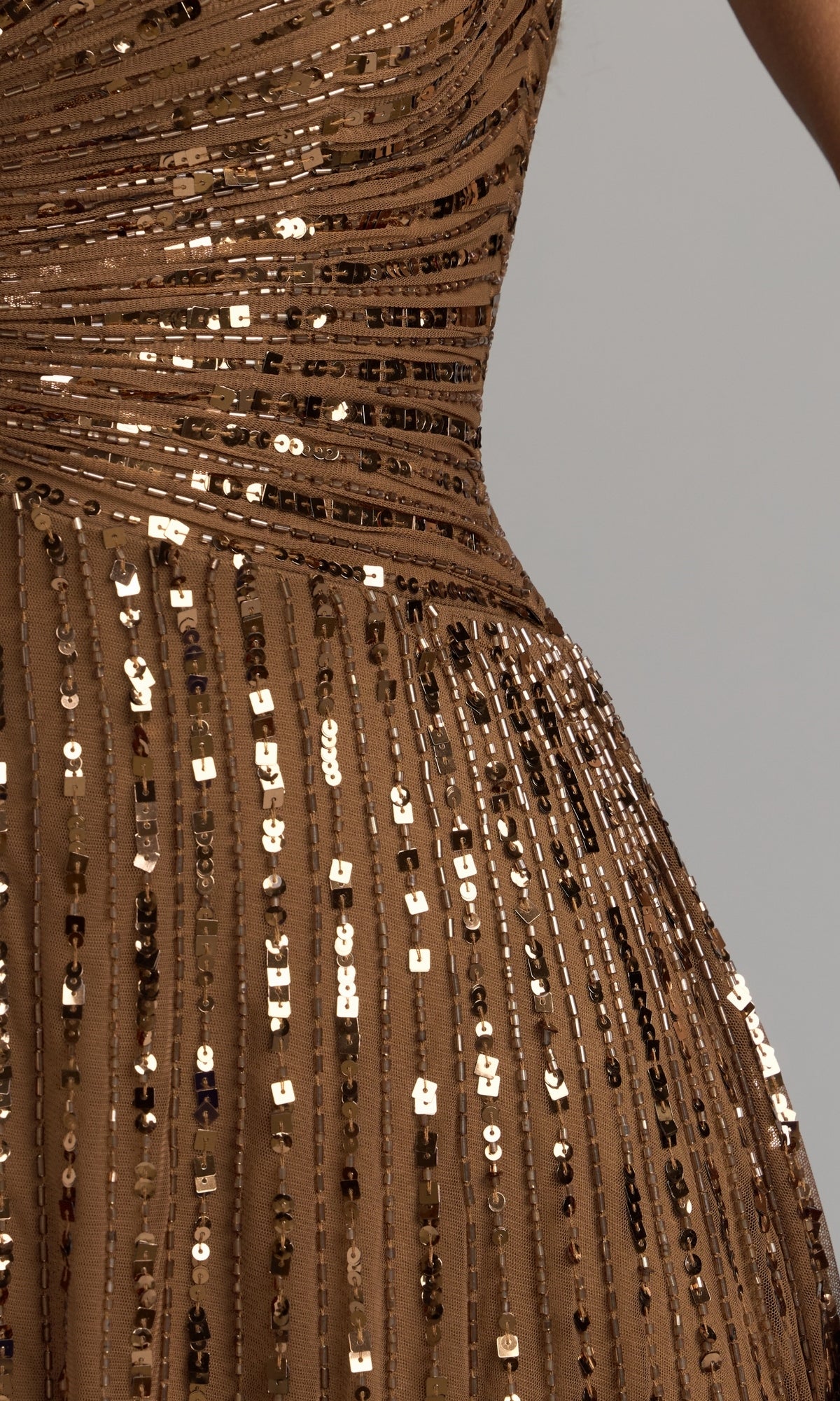 Close-up of the Mac Duggal 23042 Short Sleeve Sequin Formal Dress—a brown formal gown featuring horizontal and vertical rows of shiny sequins, with part of a person’s waist and arm visible against a neutral background, reminiscent of an elegant mother of the bride dress.