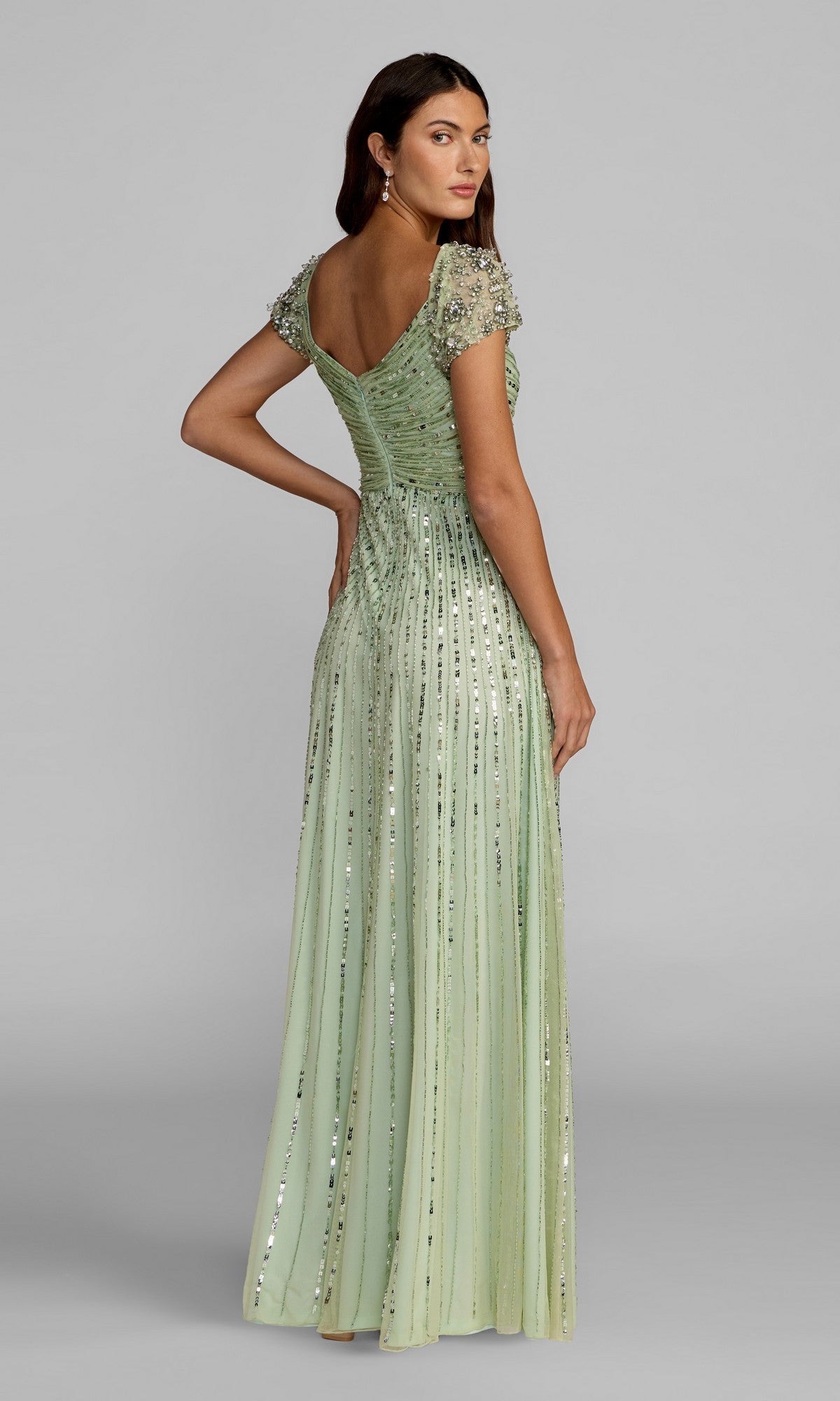 Woman in the Mac Duggal 23042 Short Sleeve Sequin Formal Dress, featuring light green sequins, ruched fabric, and embellished short sleeves—an elegant mother of the bride look.