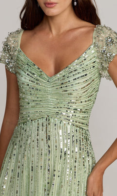 A woman wearing the Mac Duggal 23042 short sleeve sequin formal dress in light green, featuring a V-neckline, ruched bodice, and beaded sleeves—an elegant choice for a stylish mother of the bride.