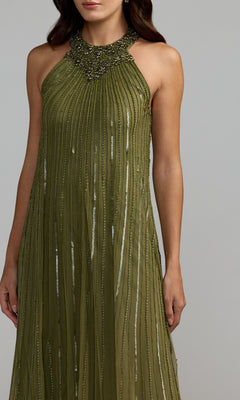 Woman wearing the Mac Duggal 23043 long formal dress in olive green, featuring a sleeveless design with a beaded neckline and vertical textured stripes, standing against a plain gray background. This look embodies the sophisticated elegance of Mac Duggal designs.
