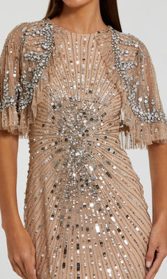 Woman wearing the Mac Duggal 23044 Capelet Long Beaded Formal Dress in beige, detailed with silver sequins and beads in radiating patterns and featuring sheer, embellished short sleeves.