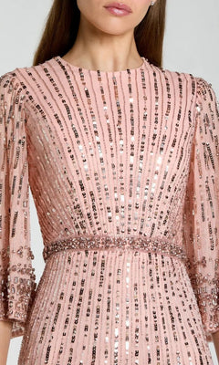 A woman wearing the Mac Duggal 23045 Long Formal Dress in pink, designed with vertical sequin stripes and beaded accents at the waist and sleeves.