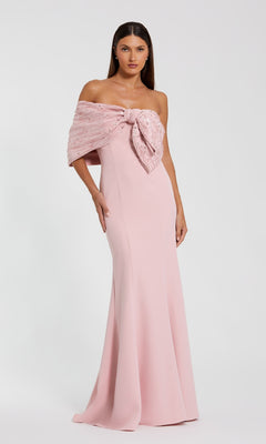 A woman models the Mac Duggal 2305 Draped Long Pink Formal Dress, featuring a textured bow detail on the bodice, as she stands against a plain white background.