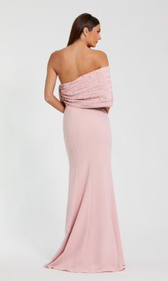 A woman in the Draped Long Pink Formal Dress: Mac Duggal 2305, a floor-length off-the-shoulder gown with beaded details, stands facing away against a plain white background.