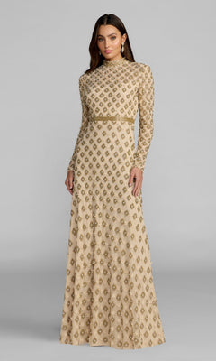 A woman wears the Mac Duggal 23087 long formal dress in champagne gold, featuring long sleeves and embellished patterns, as she stands against a plain gray background.