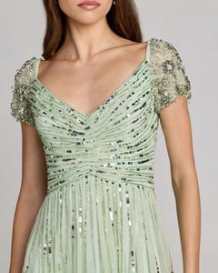 A woman wearing the Midi Party Dress: Mac Duggal 23098, a light green sequin midi dress with an a-line skirt, beaded short sleeves, and a ruched bodice.