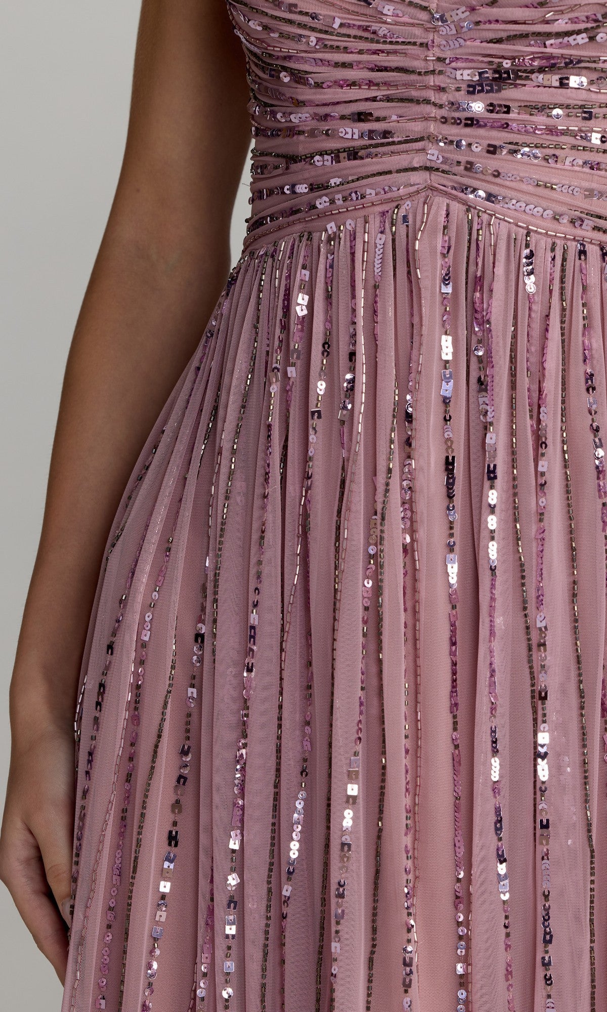 A close-up of the Mac Duggal 23098 midi party dress, featuring vertical mauve sequined stripes and ruched detailing at the bodice, worn by a person with a bare arm visible.