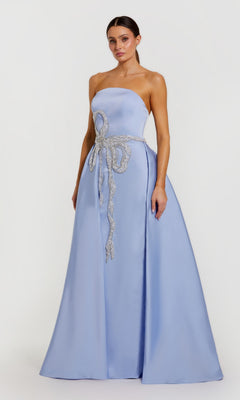 A woman models the Mac Duggal 2317 long formal dress in powder blue, featuring a strapless satin design and jeweled bow at the waist, standing against a plain white background.