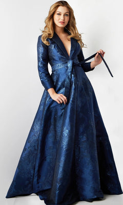 A woman wearing the Long Formal Dress: Jovani 23178, a designer gown featuring a long silhouette, dark blue color, floral pattern, and belted waist, stands against a plain white background.