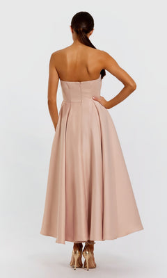 A woman stands with her back to the camera, wearing the Mac Duggal 2330 Emerald Tea-Length Formal Dress and high heels against a plain background.