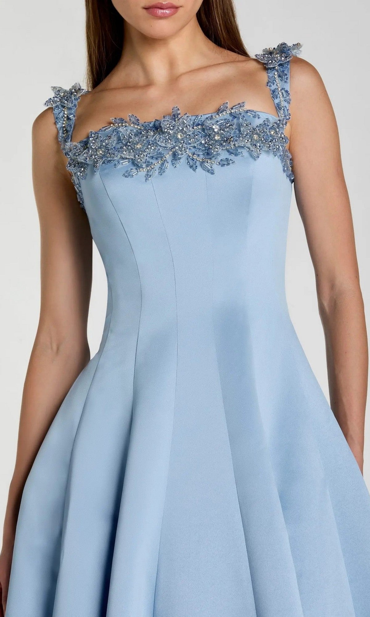 A woman wearing the Long Formal Dress: Mac Duggal 2337, a sleeveless light blue gown featuring floral bead embellishments along the neckline and straps, shown from shoulders to knees.
