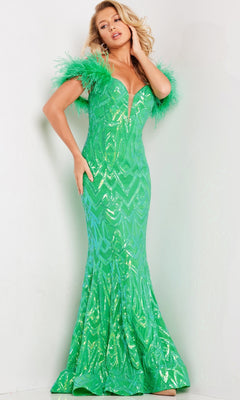 A woman poses in the Jovani Feather-Trim Long Sequin Prom Dress 23383—a fitted, floor-length green gown with a deep V neckline and feathered sleeves—against a plain light background.