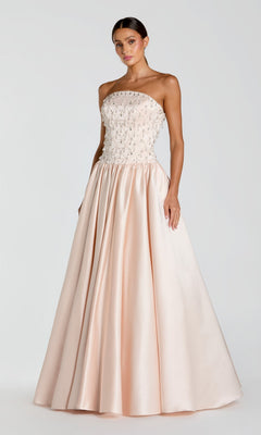 A woman stands wearing the Mac Duggal 2354 Long Formal Dress—a strapless porcelain satin gown with a beaded bodice and a full, floor-length skirt—set against a plain light background.
