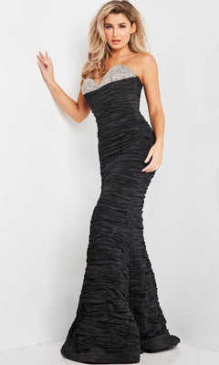 A woman models the Jovani Beaded-Bust Long Strapless Prom Dress 23546, featuring textured black fabric, a beaded sweetheart neckline, and a silver embellished bodice, against a white background.