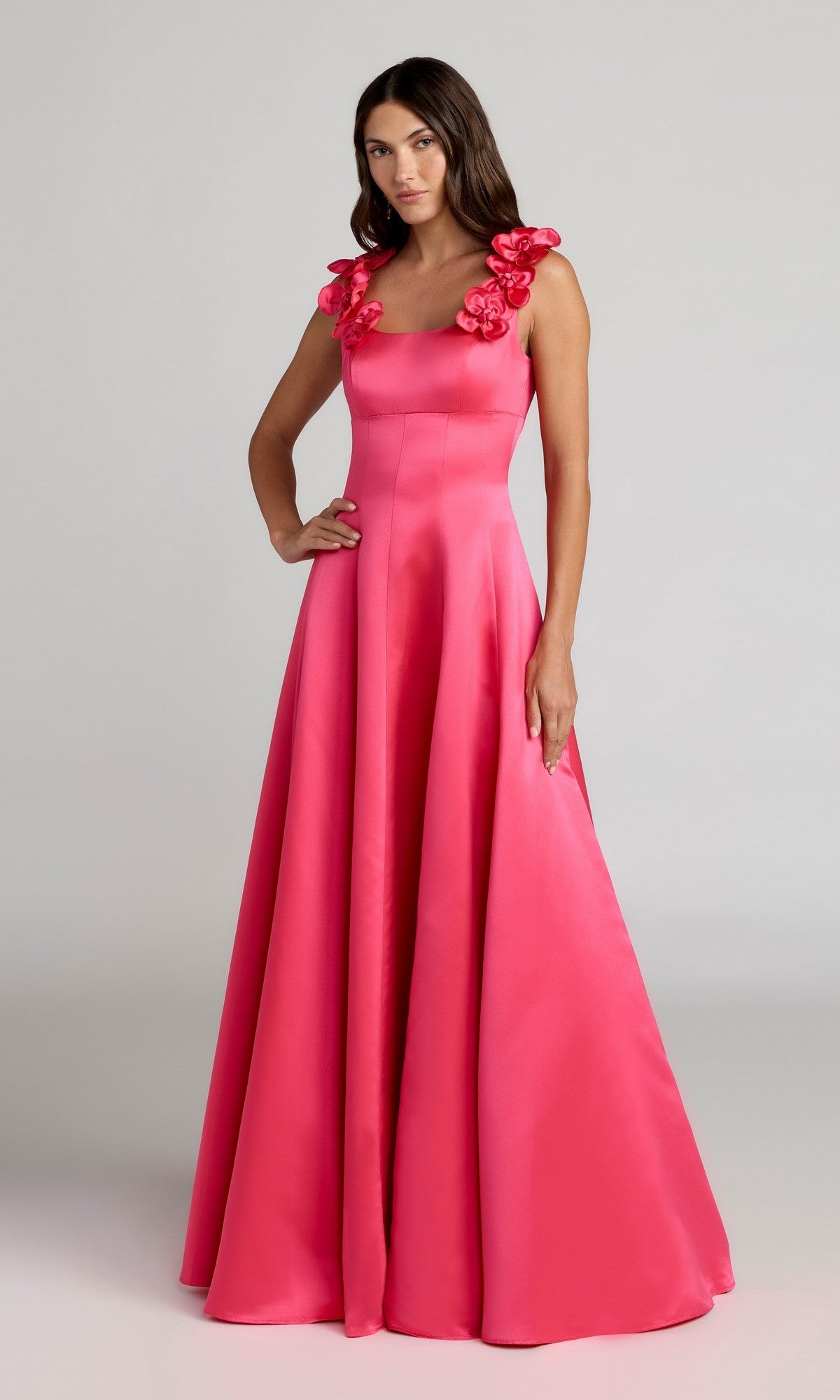 A woman stands against a plain background wearing the floor-length, sleeveless Mac Duggal 2359 long formal dress in hot pink satin, featuring floral shoulder details.
