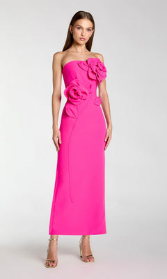 A woman stands against a plain light background wearing the Mac Duggal 2361 Long Formal Dress in hot pink, a strapless crepe midi dress embellished with large 3D floral appliques on the bodice, paired with gold high-heeled sandals.