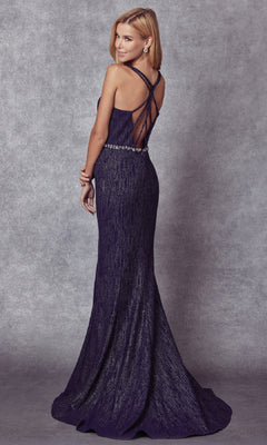 A woman faces away against a gray textured backdrop, wearing the Juliet 237 long prom dress—a floor-length, dark purple, form-fitting gown with a strappy open back.