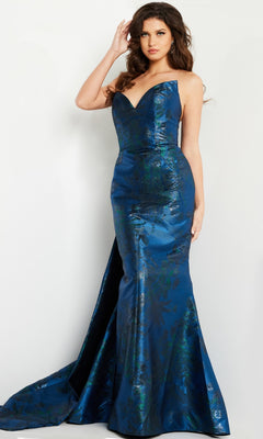 A woman stands in the Jovani 23898 Navy Blue Long Formal Dress—a strapless, floor-length mermaid gown with a slight train and metallic floral pattern—set against a plain white background.
