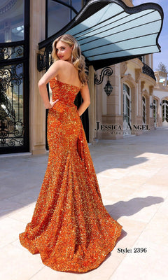 A woman in a vibrant orange, strapless Long Sequin Prom Dress (Jessica Angel 2396) stands outdoors by an elegant building, with the dress’s label and style number visible in the lower right corner.