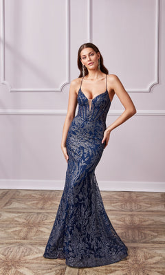 Wearing the Long Navy Glitter Prom Dress: Aerie Couture 239, a woman poses against a light-paneled wall in this elegant mermaid gown featuring silver lace details and thin straps.