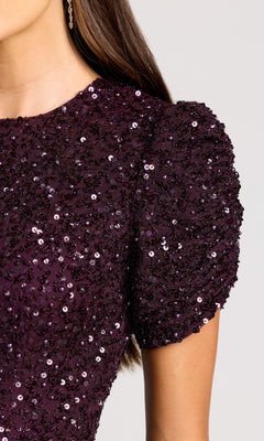 Close-up of a person wearing the Mac Duggal 24003 Short Sleeve Sequin Formal Dress in dark purple, featuring puffed short sleeves and shimmering sequins, shown from shoulder to mid-torso.