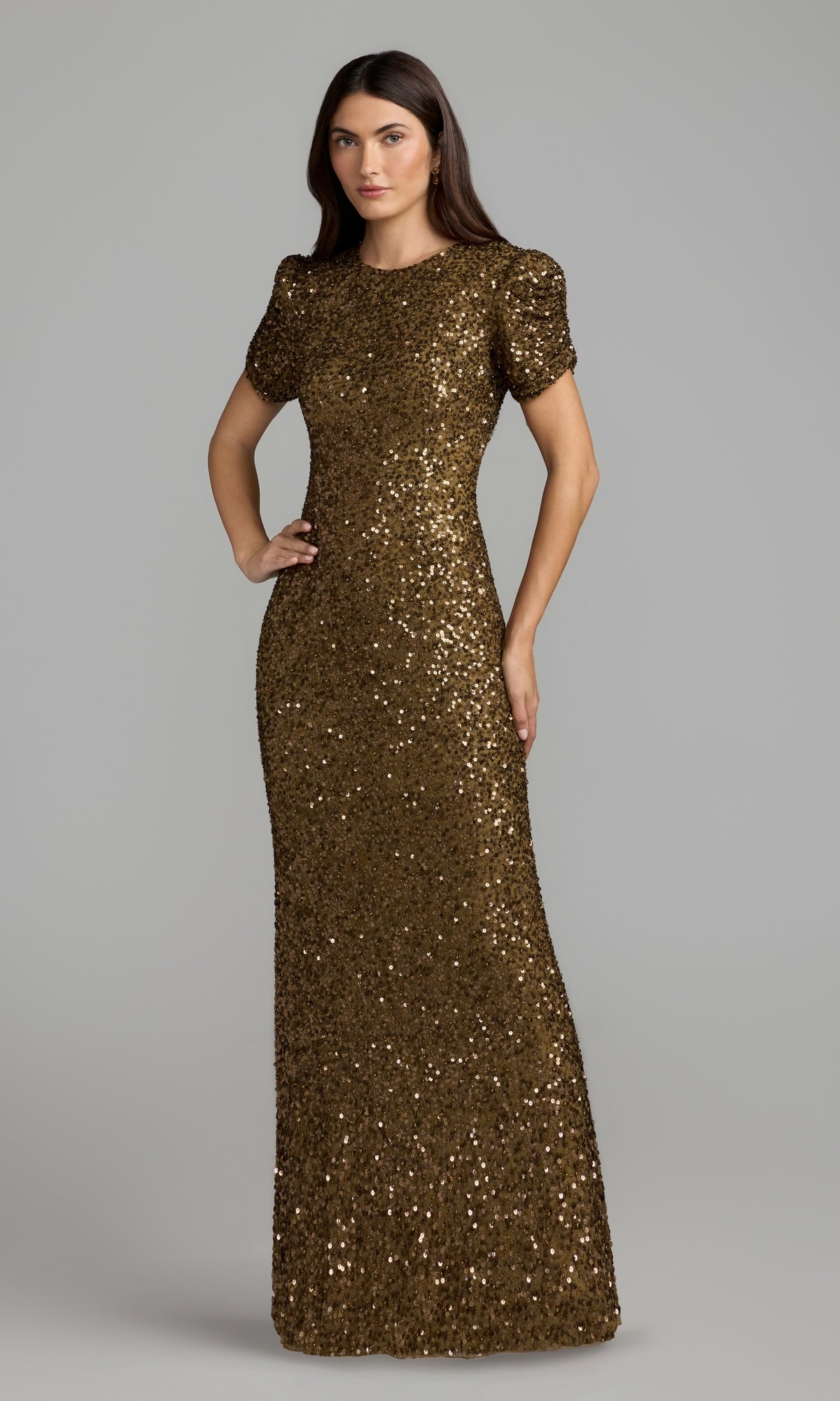 A woman wearing the Mac Duggal 24003 short sleeve sequin formal dress in chocolate stands against a plain gray background, posing with one hand on her hip.