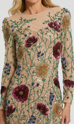 A woman wears the Short Party Dress: Mac Duggal 24006, a sheer, long-sleeve mini dress featuring sequin floral embroidery in red, gold, green, and blue on a nude background. The beaded floral design is visible on her upper torso and arms.