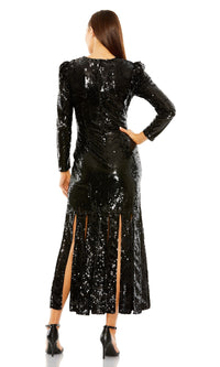 A woman stands facing away, wearing the Mac Duggal 24008 midi black sequin formal dress with multiple back slits and black high-heeled sandals.