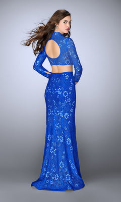 Woman in the La Femme Two-Piece High-Neck Lace Prom Dress 24013—an elegant blue lace gown with open back—stands against a plain backdrop, looking over her shoulder.