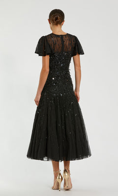 A woman faces away, wearing the Mac Duggal 24018 Brown Tea-Length Party Dress—a semi-formal party dress—paired with gold high heels.