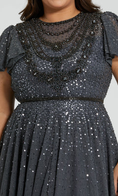 A person wearing the Plus-Size Charcoal Formal Dress: Mac Duggal 24025, a dark gray short-sleeve dress with sequins and black beaded accents on the chest and waist.