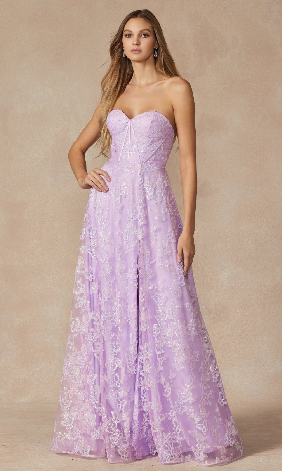 A woman stands against a neutral background wearing the Juliet 2403 Long Prom Dress—a strapless lavender lace gown featuring a fitted corset bodice and flowing skirt.