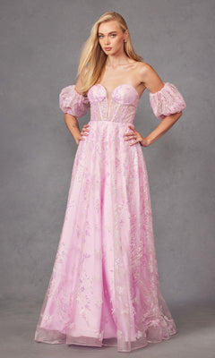 A woman in the Puff-Sleeve Strapless Long Glitter Prom Dress 2404, featuring light pink fabric, sheer puff sleeves, and floral embellishments, stands against a plain gray background.