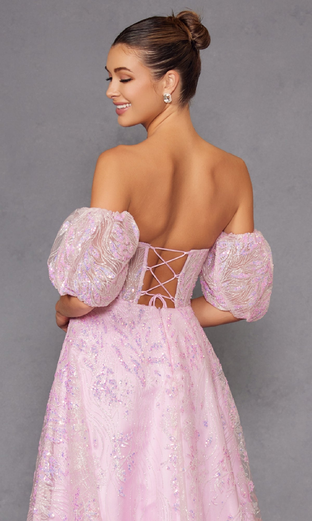 A woman in the Puff-Sleeve Strapless Long Glitter Prom Dress 2404 stands against a plain gray background, facing away and smiling.