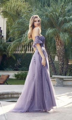 Wearing the Puff-Sleeve Strapless Glitter Prom Ball Gown 2409 in lavender, a woman stands by a pool surrounded by palm trees and lush garden landscaping.