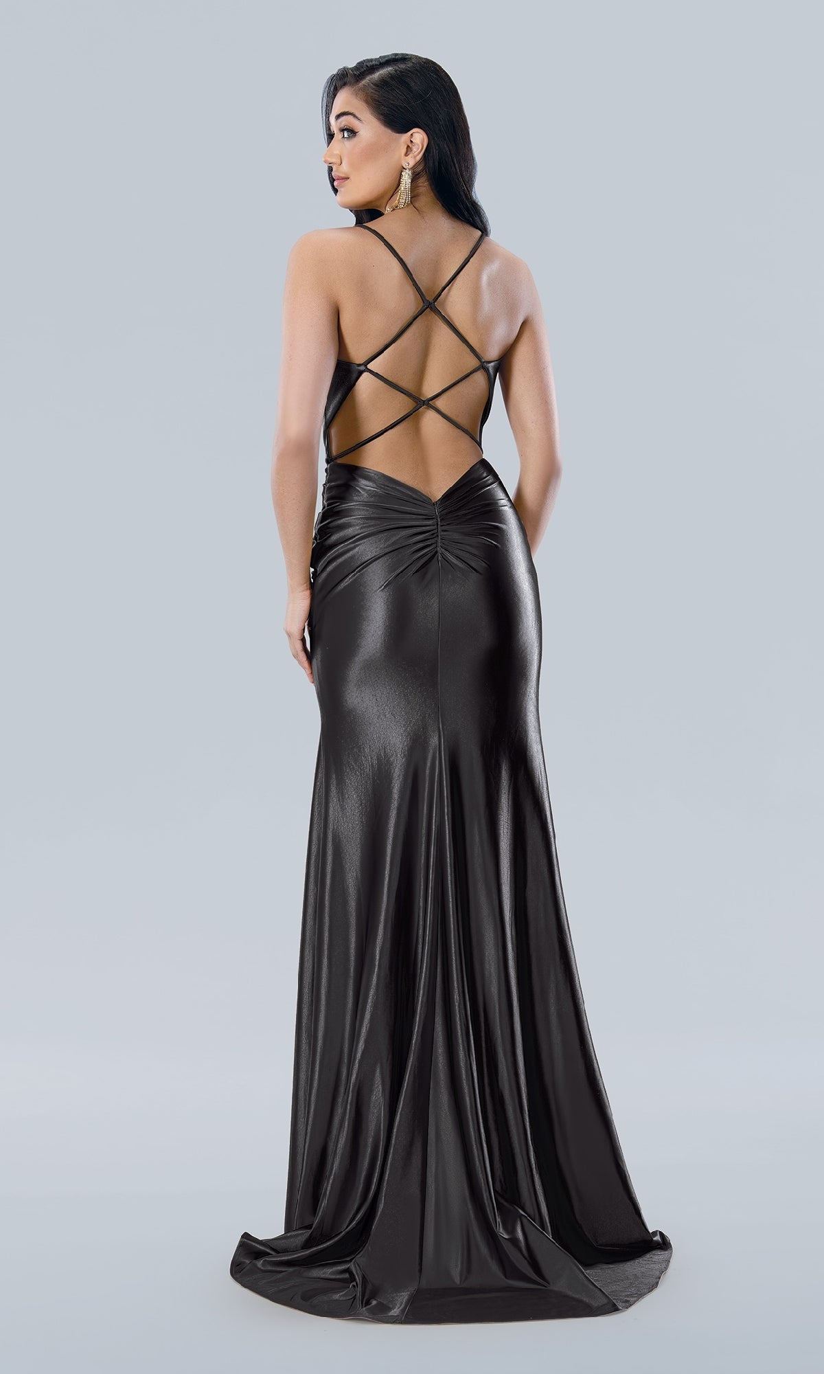 Woman wearing the Corset-Bodice Long Sweetheart Prom Dress 24108—a shiny black gown with a crisscross open back—standing and facing away from the camera against a plain light background.