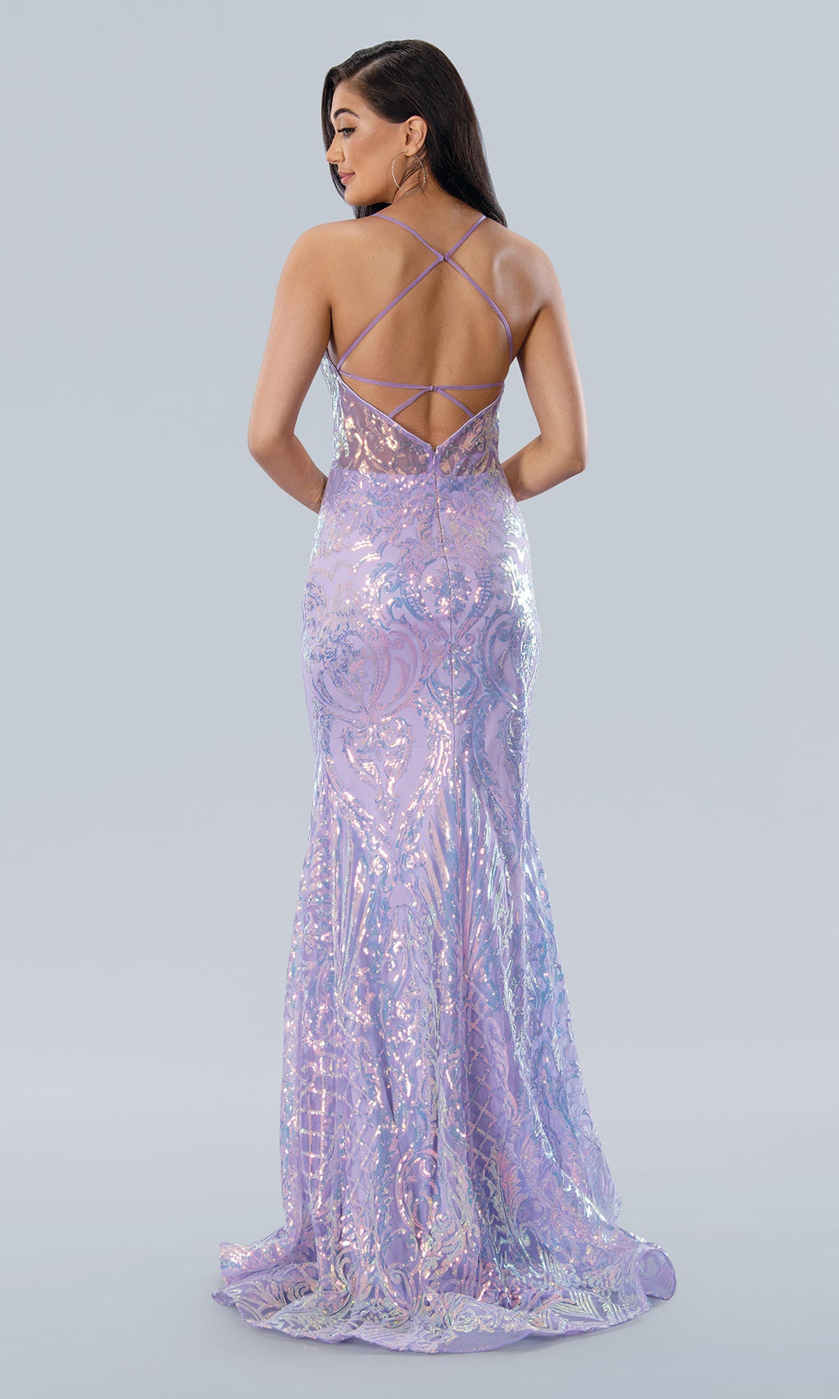 Woman wearing the Sheer-Waist Long Sequin-Print Prom Dress 24115, a floor-length, iridescent lavender fitted gown with crisscross straps on an open back, standing against a plain light gray background.