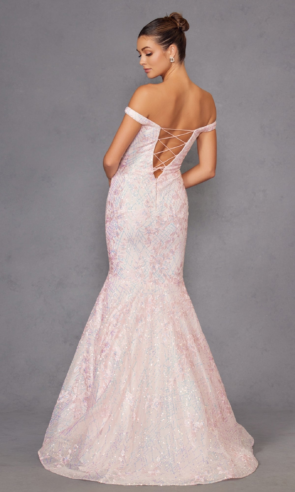 Woman wearing the Off-the-Shoulder Sequin Mermaid Prom Dress 2412 in light pink with an open lace-up back, posing against a plain gray background.