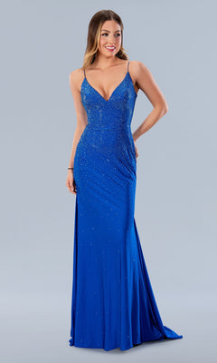 A woman poses against a plain background in the Stella Couture 24148 Laced Long Beaded Prom Dress, a fitted, floor-length royal blue gown featuring thin straps, a deep V neckline, and intricate embellishments.