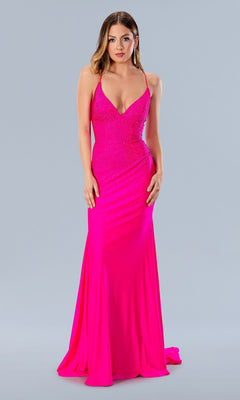 A woman wears the fitted, bright pink Stella Couture 24148 Laced Long Beaded Prom Dress with thin straps and a deep neckline, standing against a plain light gray background.